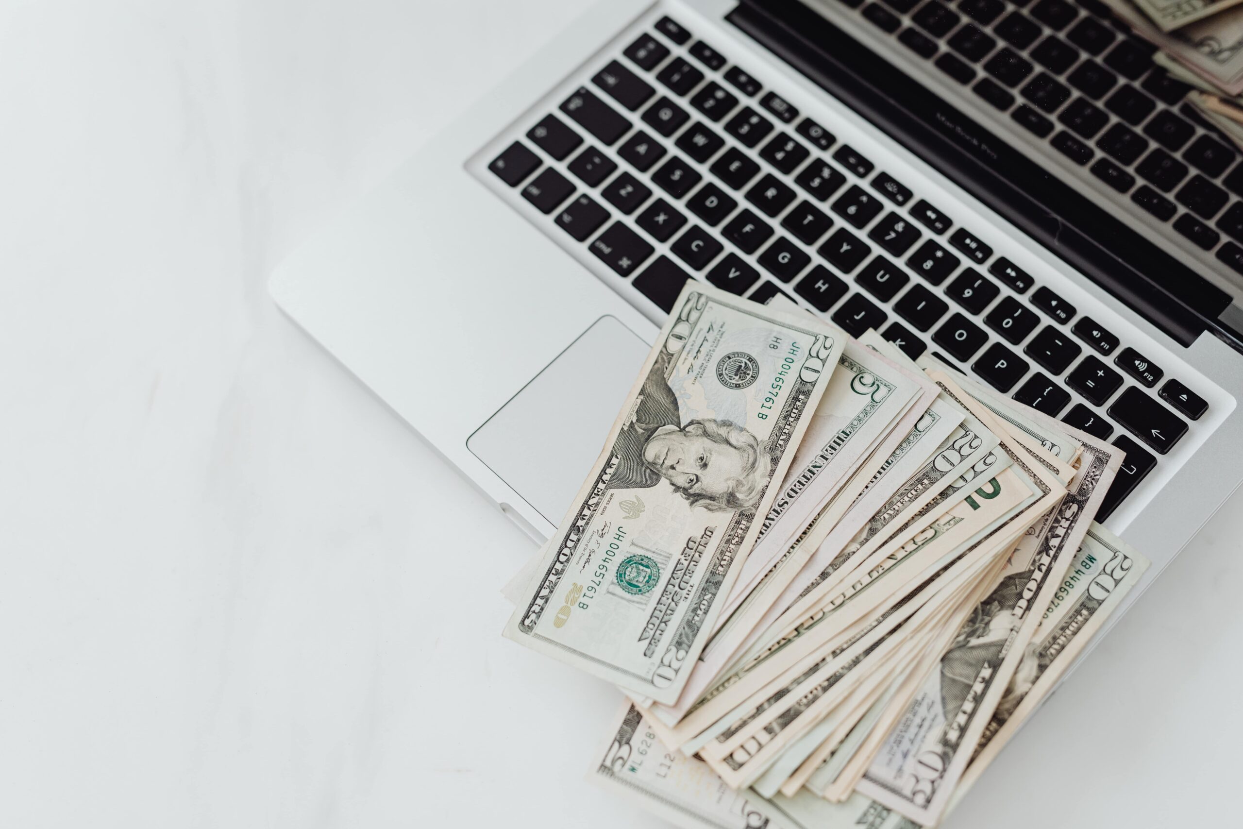 Image of money piled messily on top of a laptop